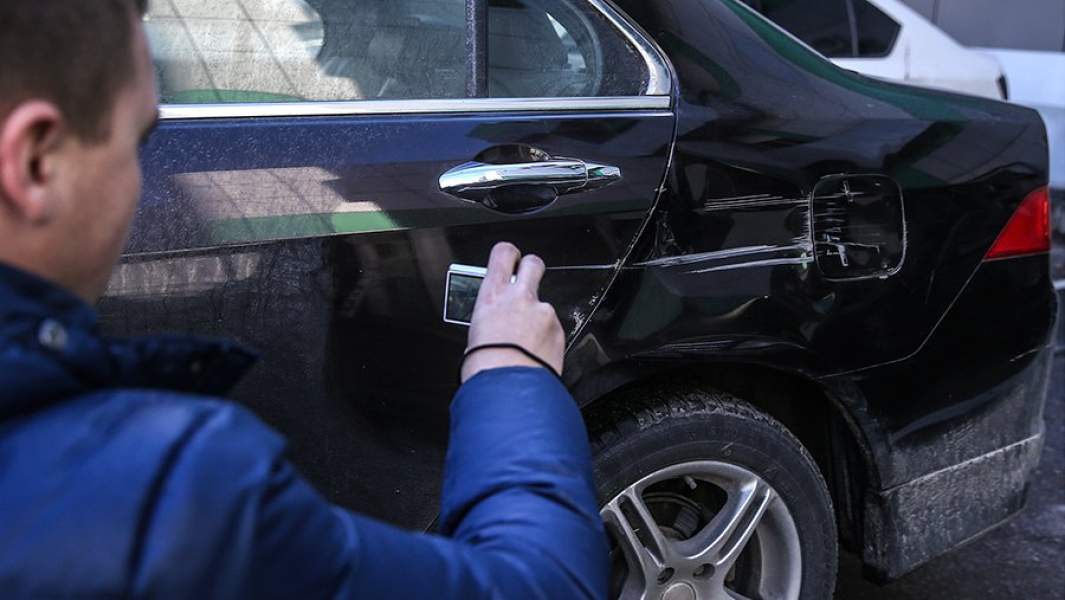 Сотрудник центра выплат страховой компании во время осмотра повреждений автомобиля