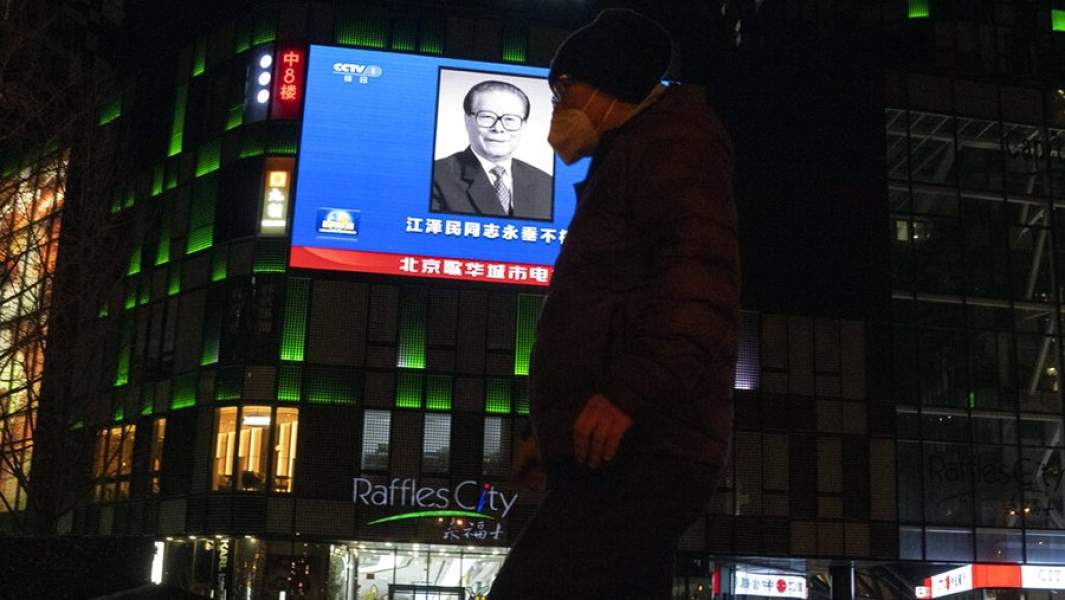 Фотография покойного президента Китая Цзян Цзэминя на большом экране во время вечерней передачи новостей о его смерти в торговом центре в Пекине, среда, 30 ноября 2022 г.