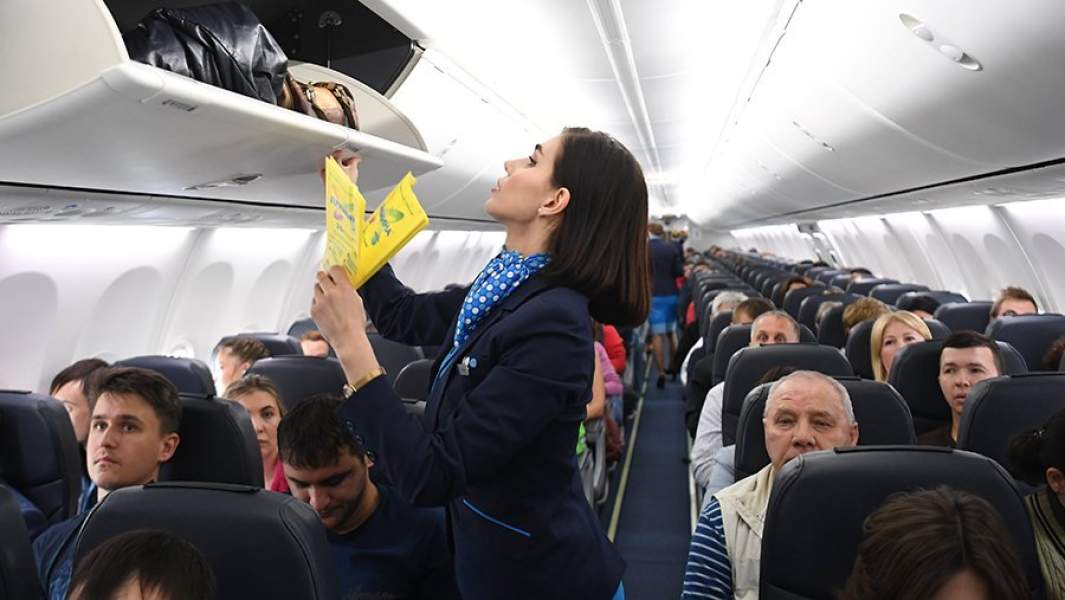 Бортпроводница проверяет багажные полки в салоне самолета