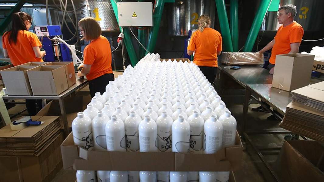 Работники в цехе по розливу и упаковки шампуней