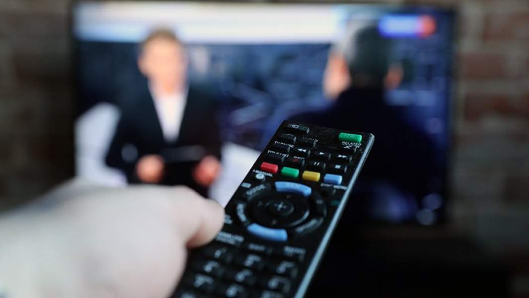 Мужчина с пультом перед телевизором