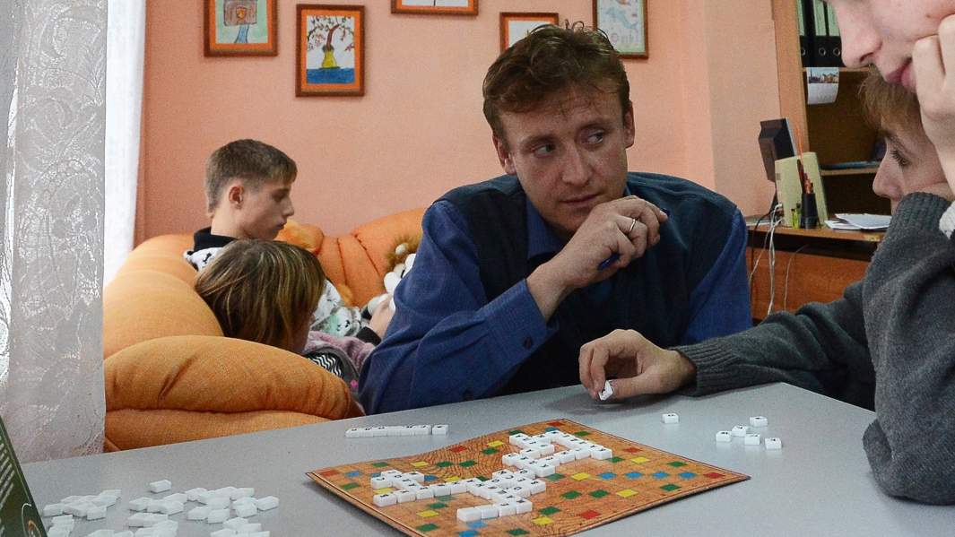 Воспитанники  детского дома играют в домино с воспитателем