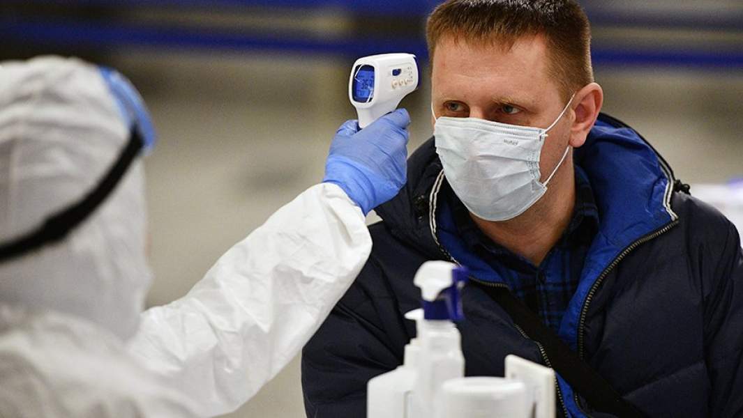 Медицинский работник измеряет температуру у пассажира в аэропорту