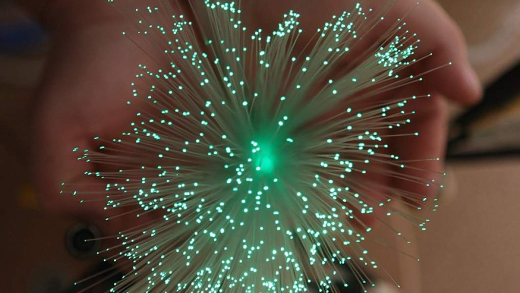 Пучок оптического волокна в руках работника участка оптоволокна предприятия по производству телекоммуникационного оборудования