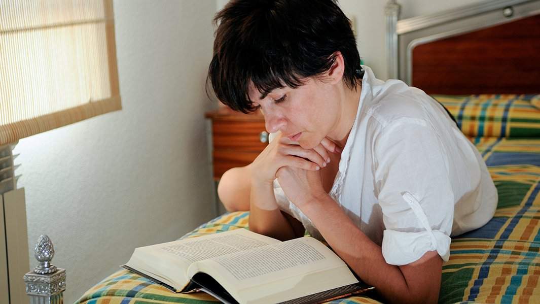 Девушка в постели читает книгу