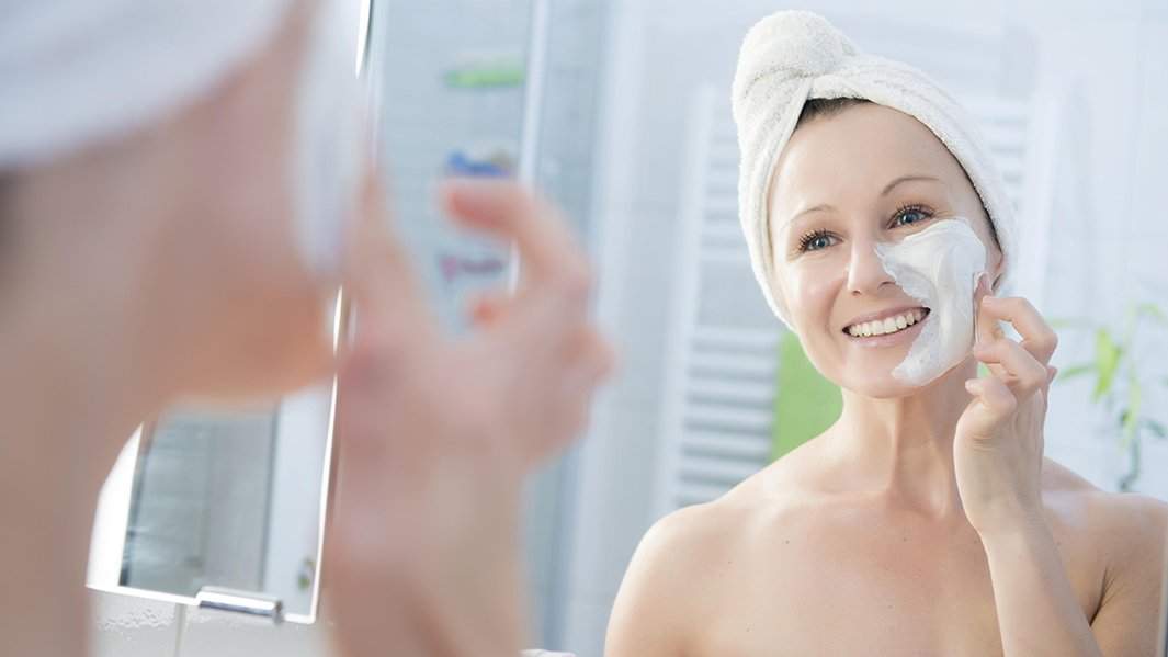 Женщина наносит крем на лицо