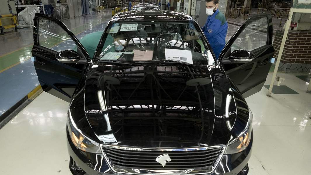 Двое иранских рабочих проверяют собранный автомобиль на производственной линии компании Iran Khodro Automaker Company 