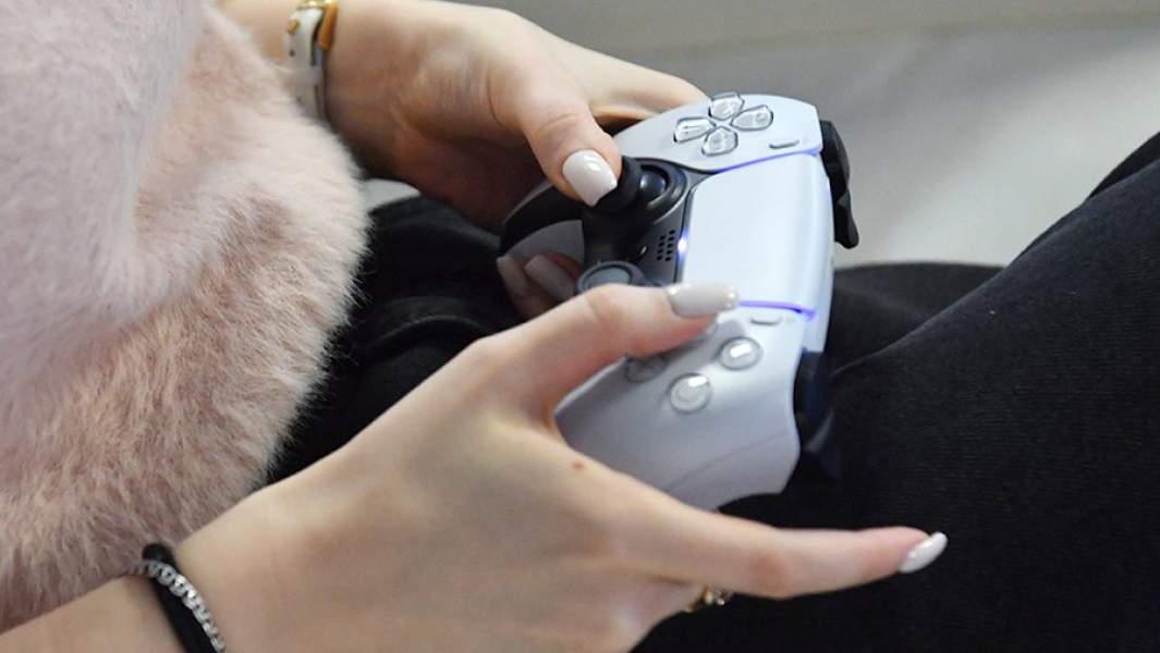 Девушка играет в игровую приставку Sony PlayStation 5
