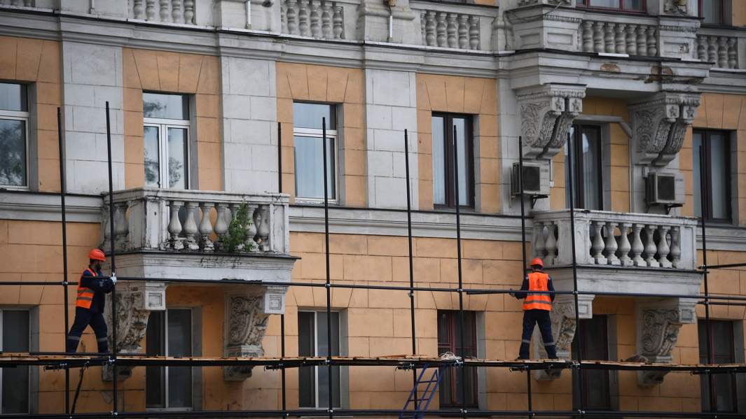 рабочие ремонтируют фасад