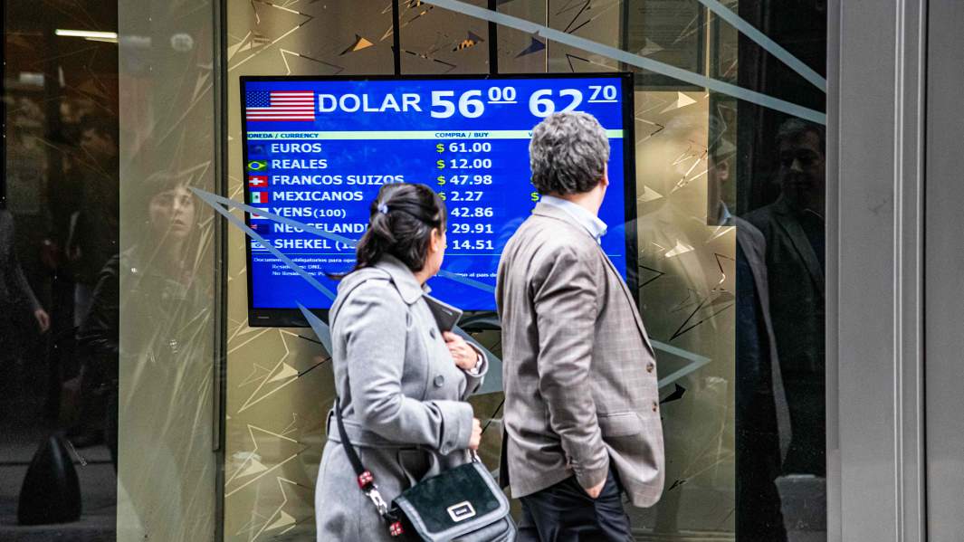 люди проходят мимо табло с курсами валют