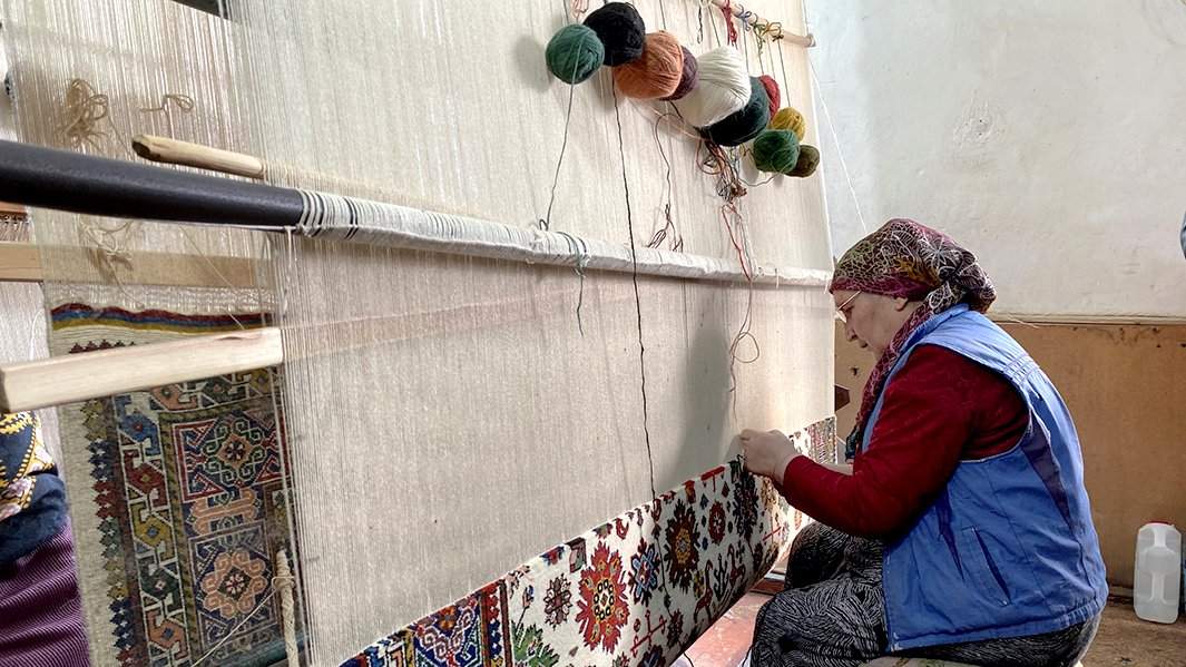 Женщина ткет ковер