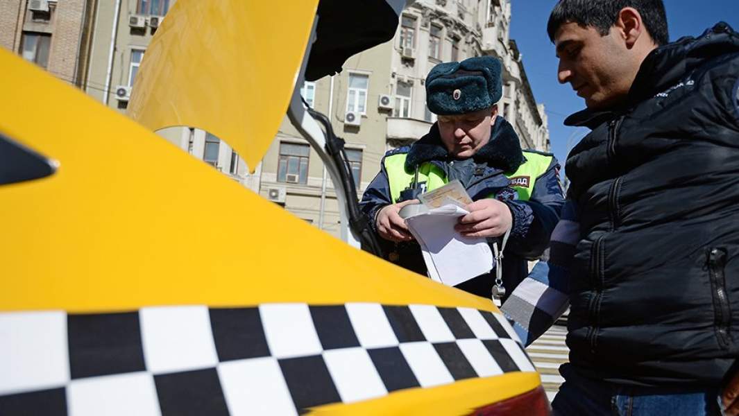 Сотрудник ГИБДД проверяет документы у водителя в рамках рейда против нелегальных таксистов
