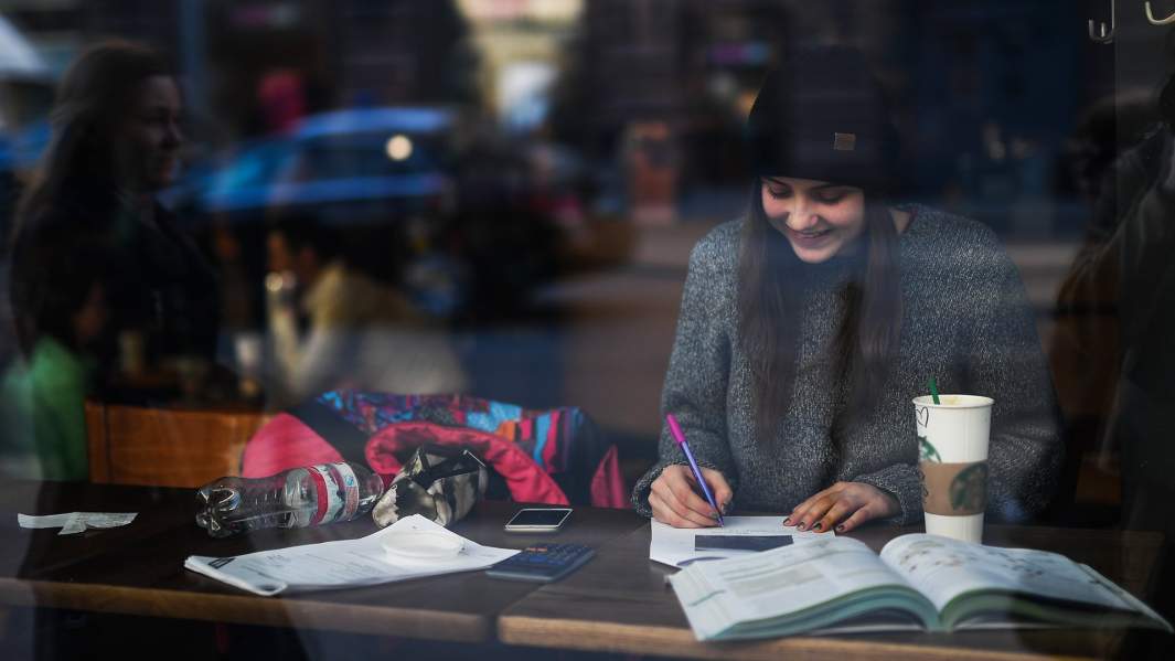 девушка ведет записи в тетради в кофейне