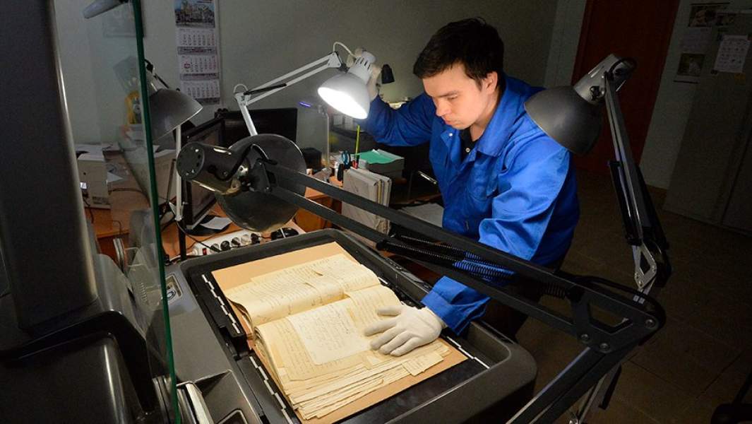 Сотрудник сканирует архивные документы в лаборатории архива