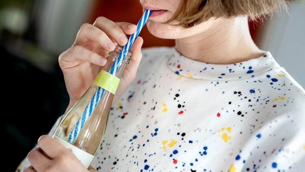 девушка пьет газировку с помощью пластиковой трубочки