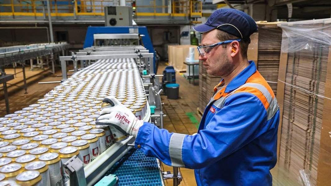 Сотрудник предприятия на производстве пивной продукции на территории завода