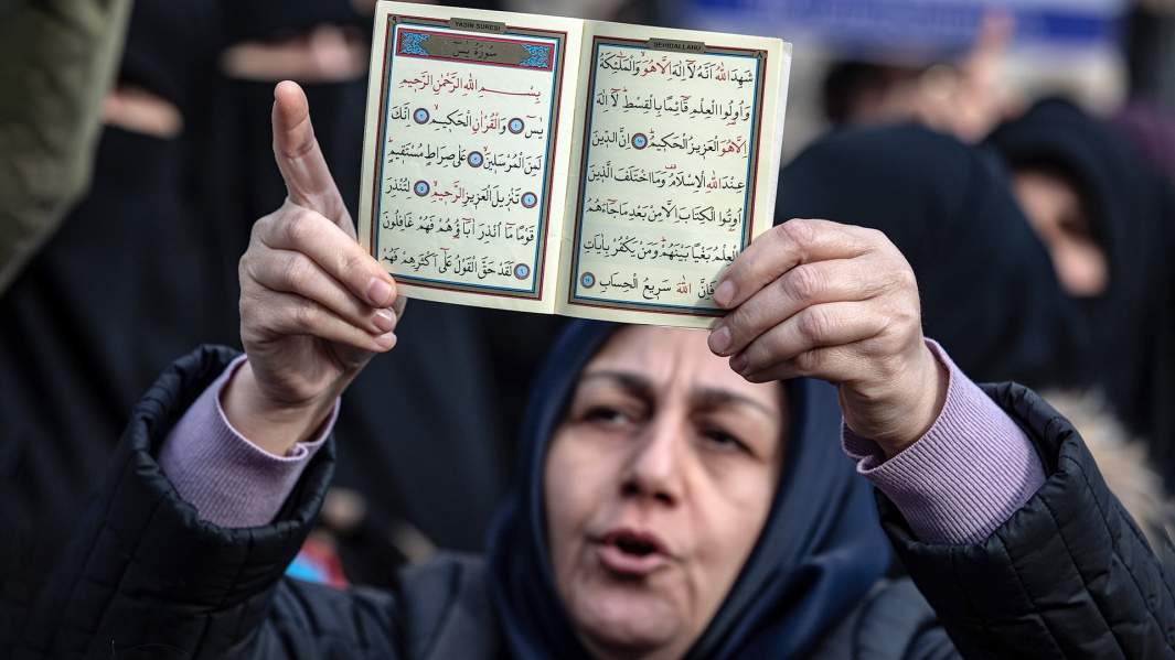 Протестующая держит Священный Коран во время демонстрации в Стамбуле возле консульства Швеции. 
