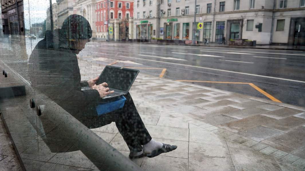 man at bus stop with laptop