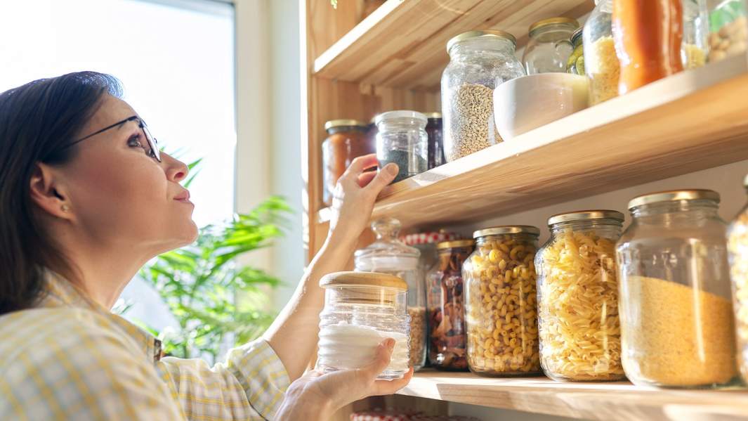 Женщина достает банку с крупой 