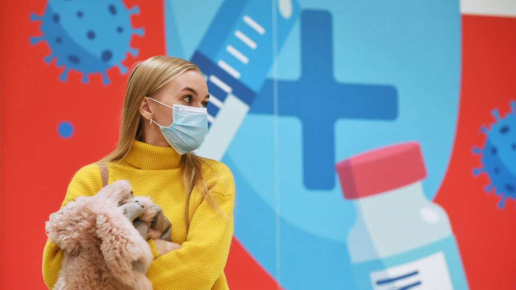 девушка на фоне плаката о вакцинации 