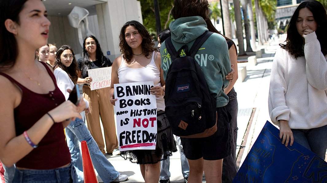 Девушка держит табличку, когда студенты устраивают выход из кампуса Майами-Дейд-колледжа Вольфсона в знак протеста против того, что чиновники образования Флориды проголосовали за запрет классных занятий по гендерной идентичности и сексуальной ориентации во всех классах государственных школ, расширяя закон, подписанный губернатором-республиканцем Роном Десантисом, 21 апреля 2023 года