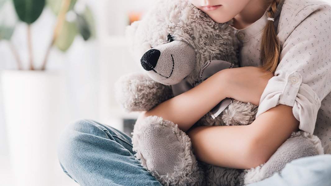 Девочка обнимает игрушечного медведя