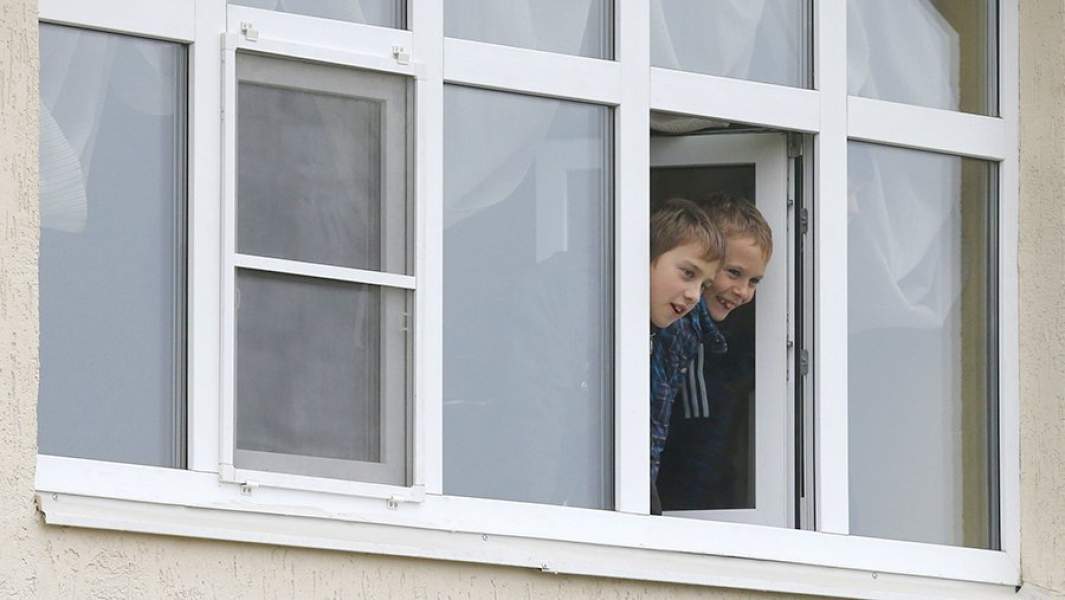 Дети смотрят из окна новой квартиры