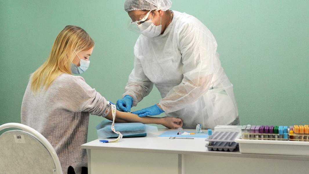 Старшая медицинская сестра проводит взятие крови у пациентки на антитела к коронавирусу COVID-19