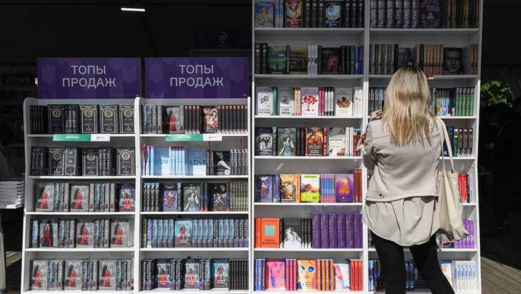 Посетительница IX книжного фестиваля «Красная площадь» у стеллажей с книгами издательства «Эксмо»