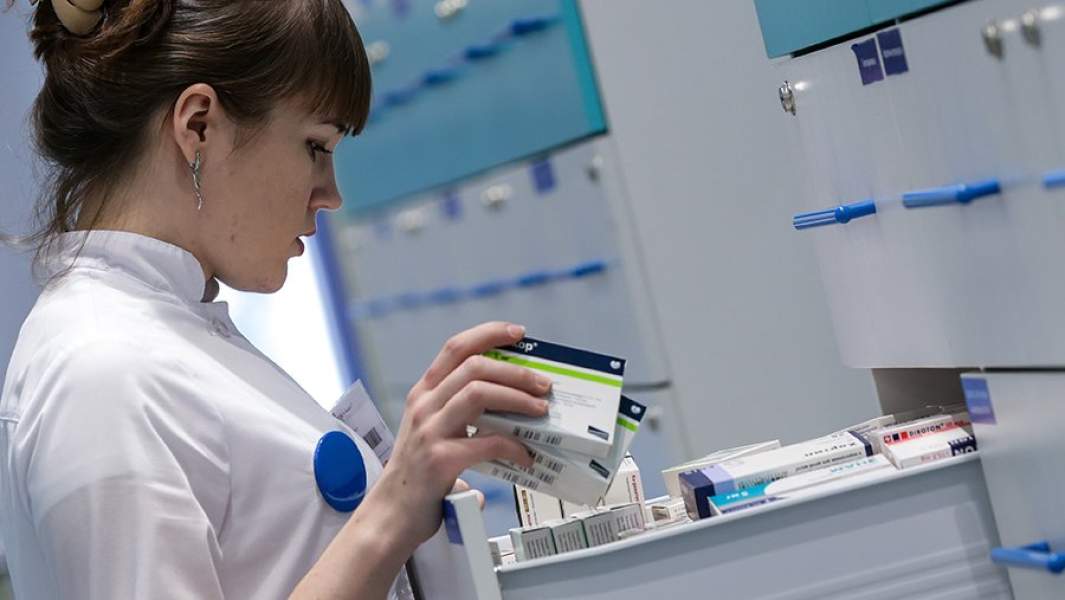 Фармацевт отпускает лекарства в аптеке