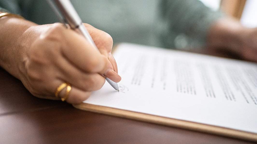 Женщина подписывает документы