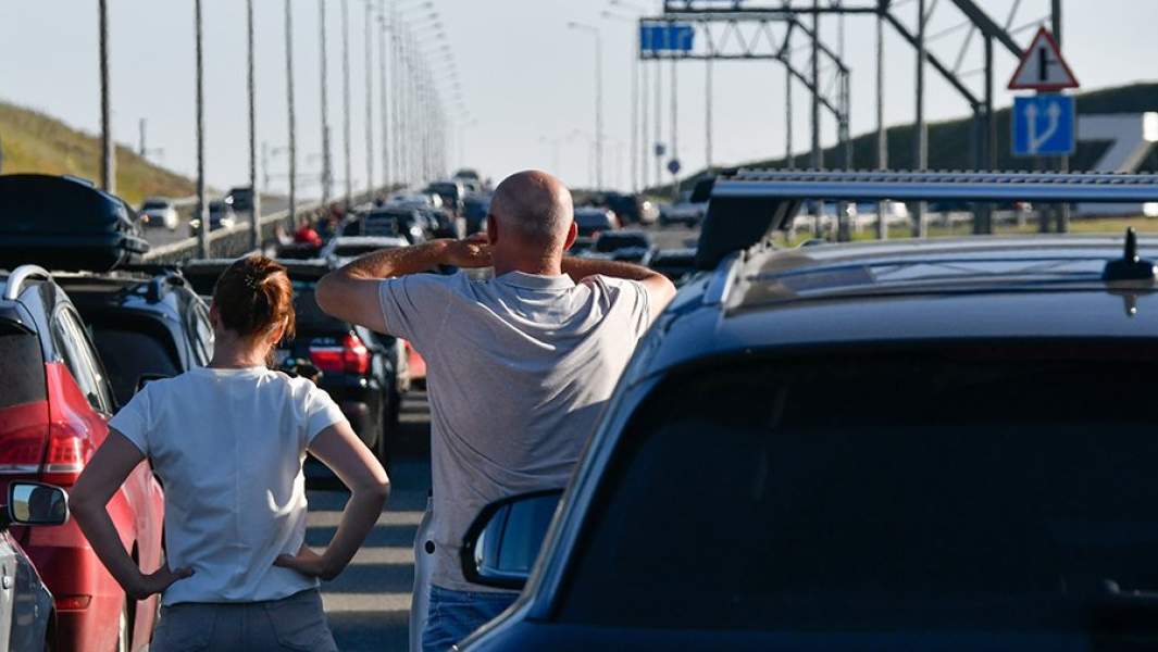Люди у автомобилей, которые стоят в очереди в сторону Крымского моста