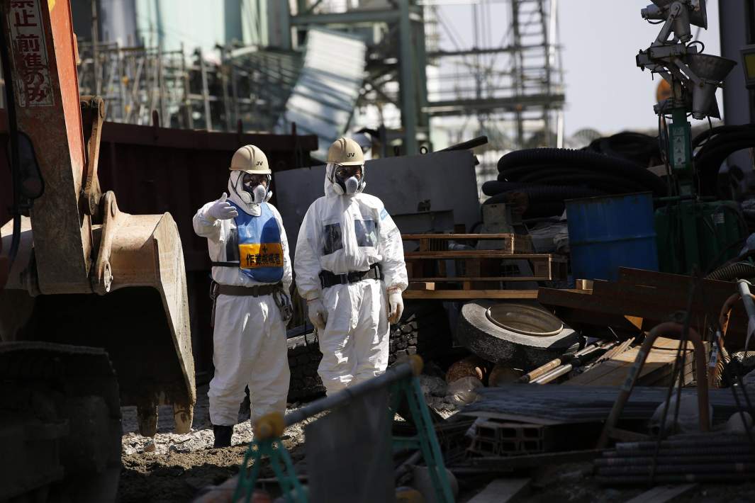 Рабочие в защитных костюмах рядом с разрушенным реактором № 4 