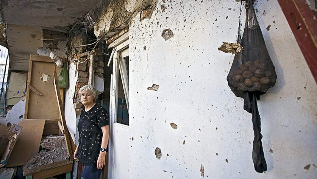 Женщина в своем доме, пострадавшем от пуль и снарядов во время обстрела Цхинвала