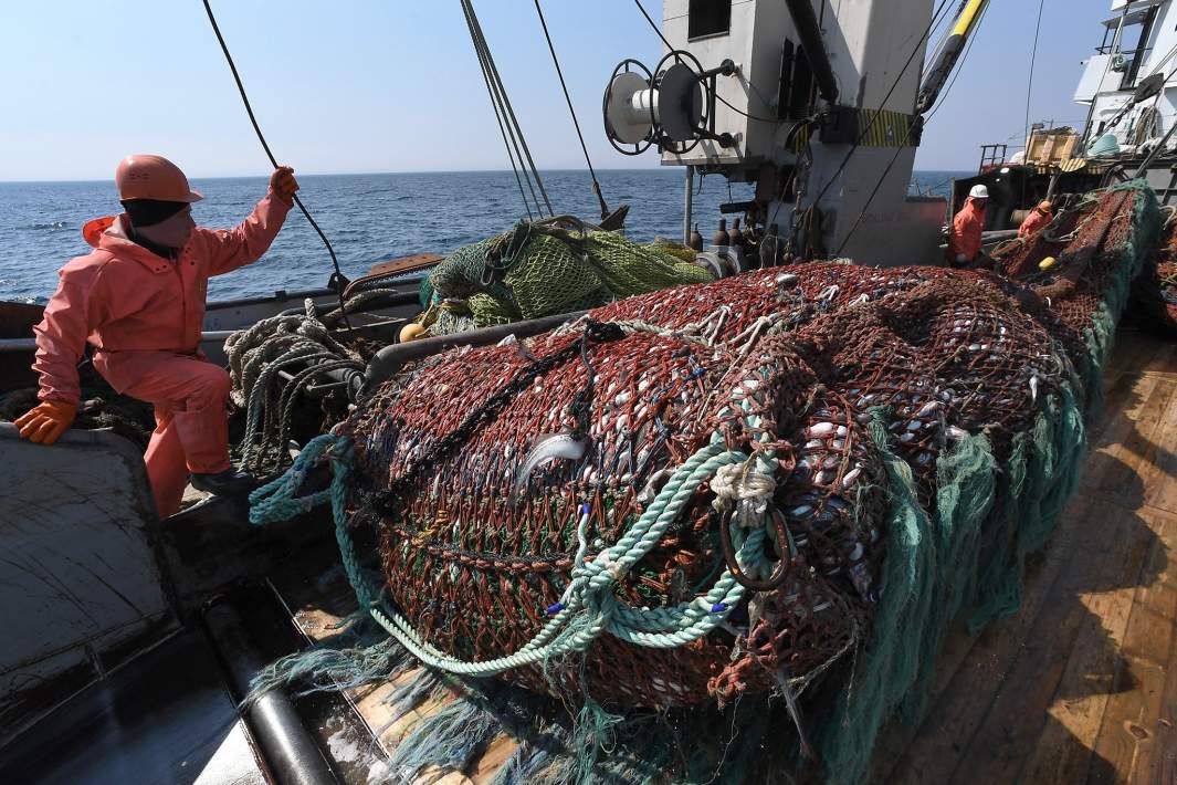 Палубная команда сейнера-траулера во время выборки донного невода в море у берегов Владивостока