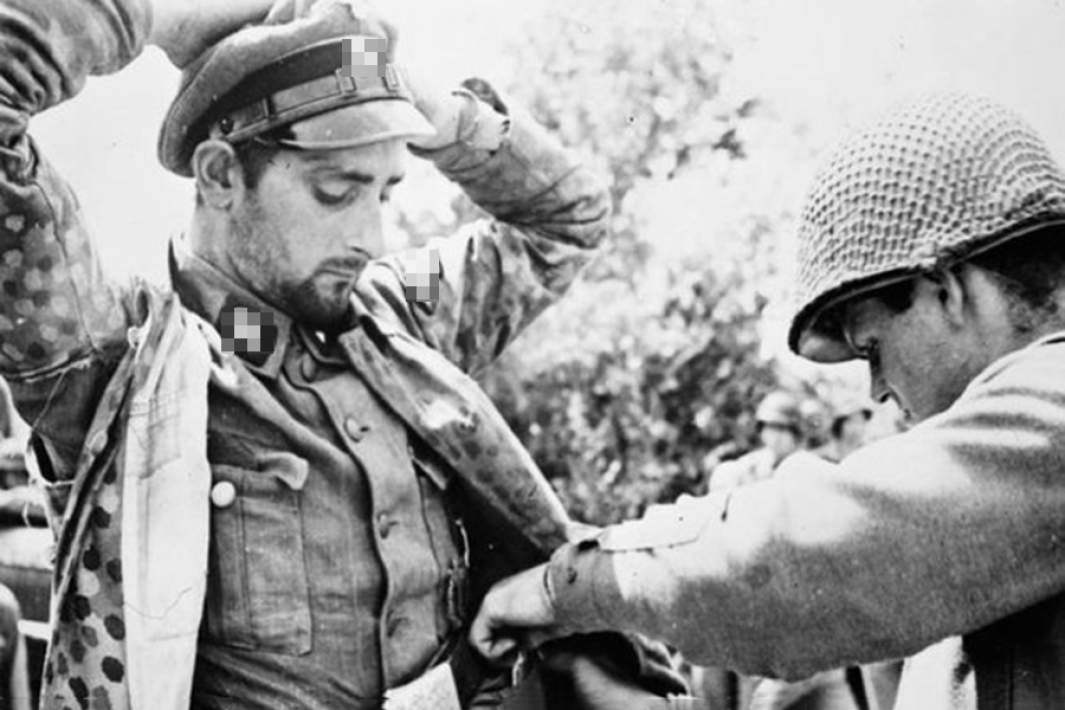 Солдат союзных войск обыскивает пленного офицера СС. 1945 год