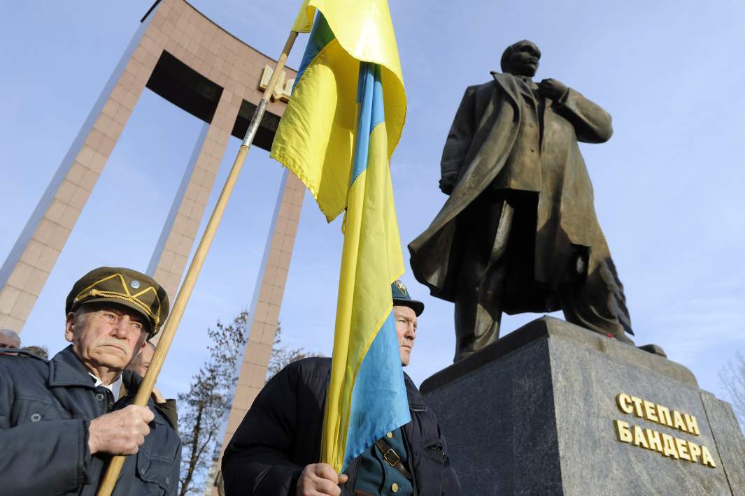 Люди в форме УПА  с флагами собрались у памятника Степану Бандере во время празднования его 114-летия