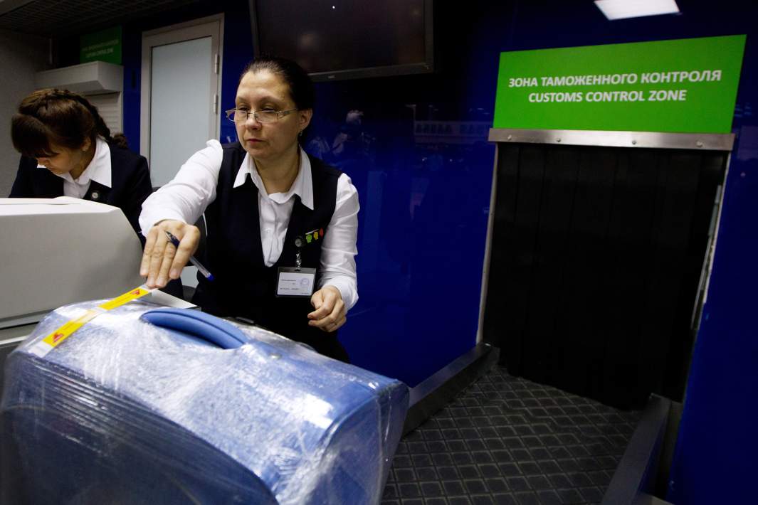 Сотрудник международного аэропорта принимает багаж во время регистрации на рейс