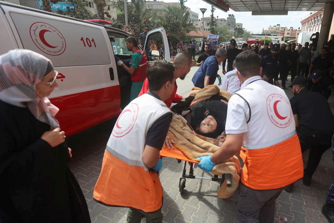 Сотрудники скорой помощи и женщина, раненная в результате израильских ударов, у больницы в Хан-Юнисе на юге сектора Газа