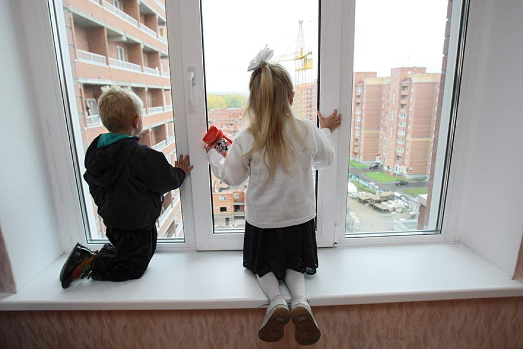Дети смотрят из окна новой квартиры