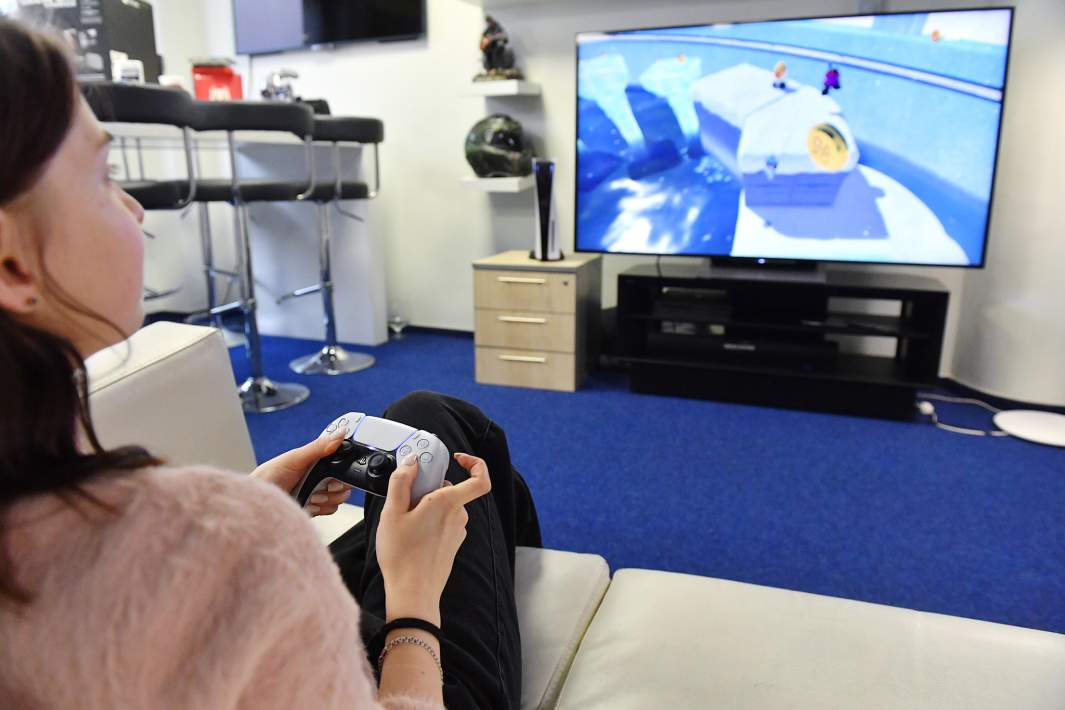 Девушка играет в игровую приставку Sony PlayStation 5