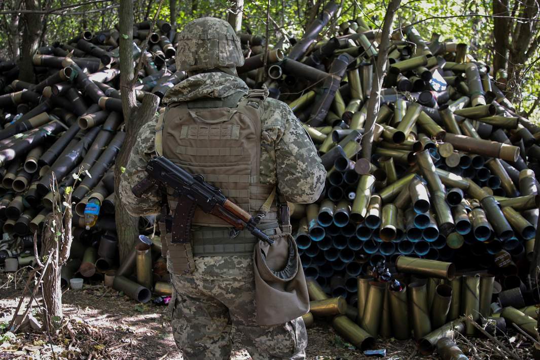Украинский военнослужащий стоит рядом с использованными гаубичными снарядами