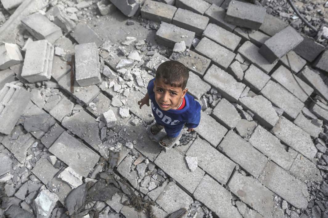 Ребенок на развалинах жилого дома лагеря для беженцев Аль-Бурейдж