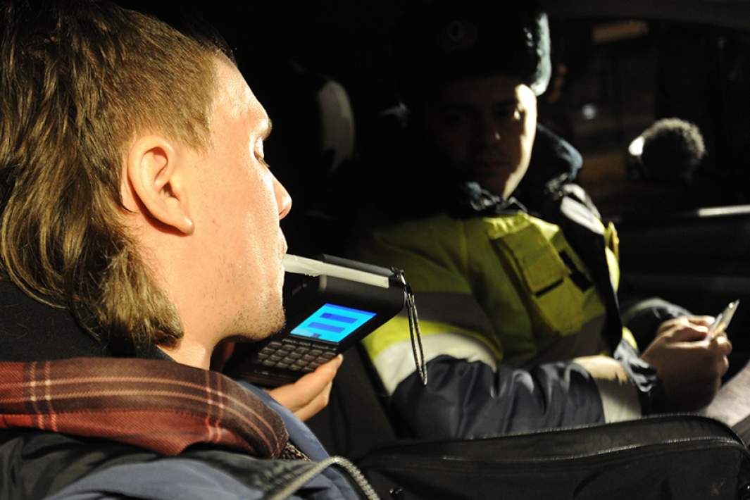 Сотрудник ГИБДД проверяет водителя алкотестером на содержание алкоголя в крови