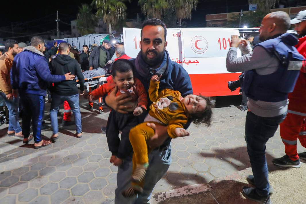Мужчина с двумя маленькими детьми, пострадавшими в результате авиаудара Израиля, у одной из больниц Газы