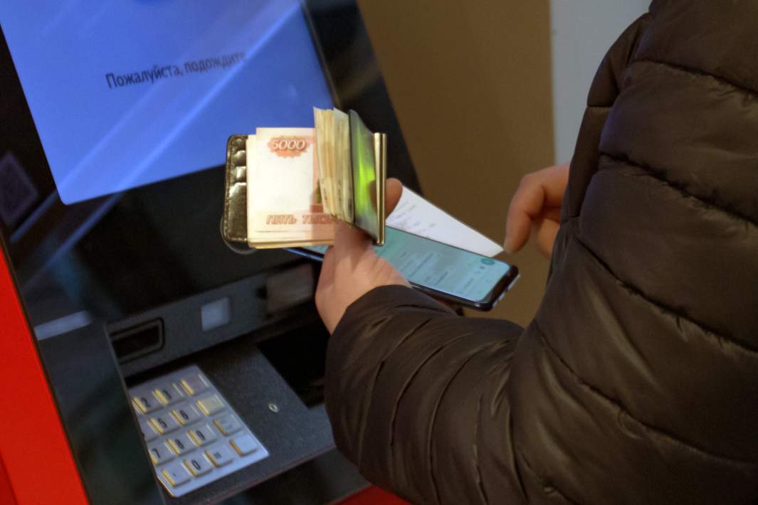 Посетитель с наличными деньгами у банкомата