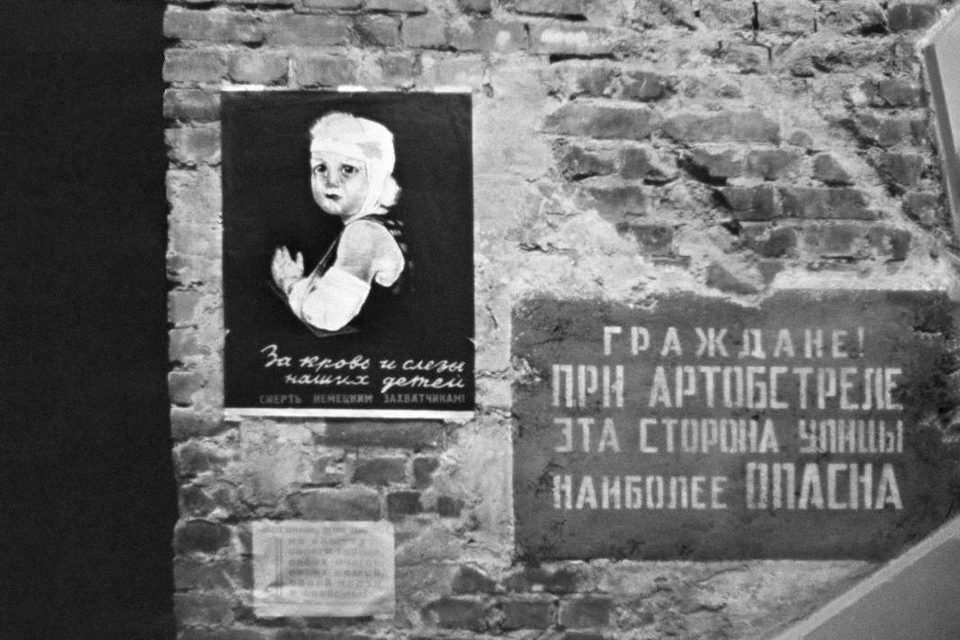 Блокадный Ленинград. Предупреждающая жителей об обстреле табличка и плакат на стене жилого дома, 1941 год