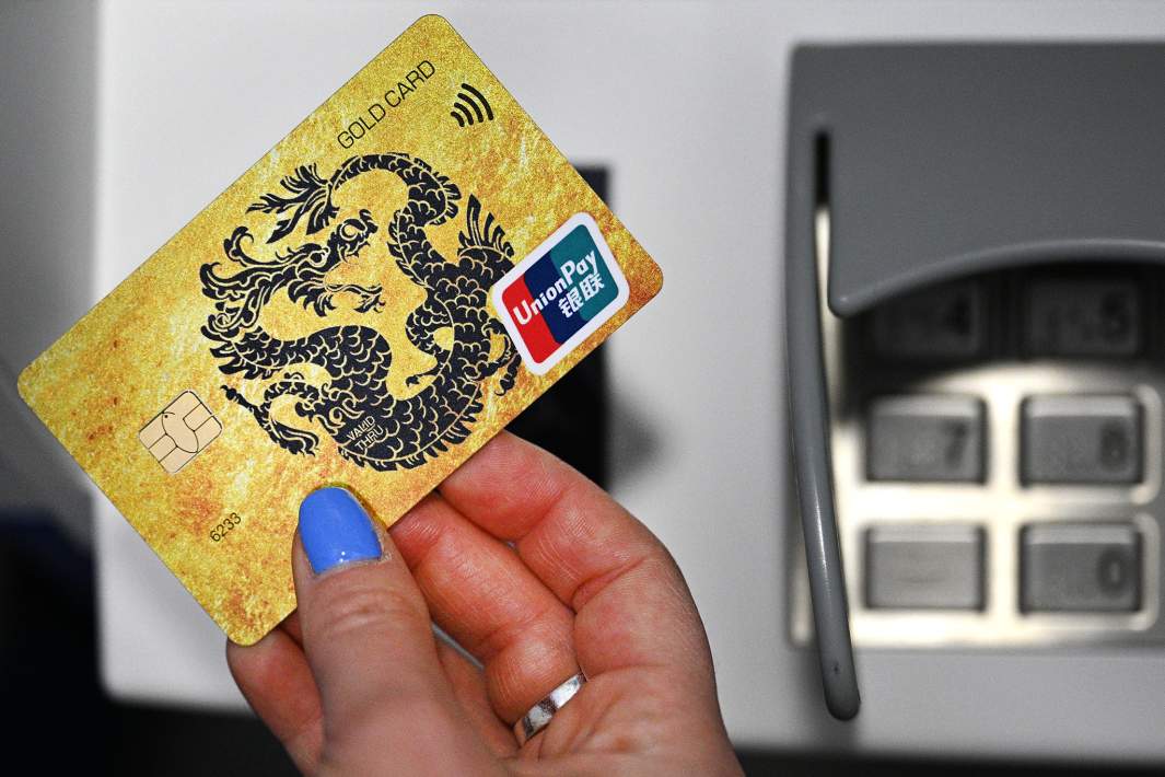 Девушка держит у банкомата карту международной платежной системы UnionPay