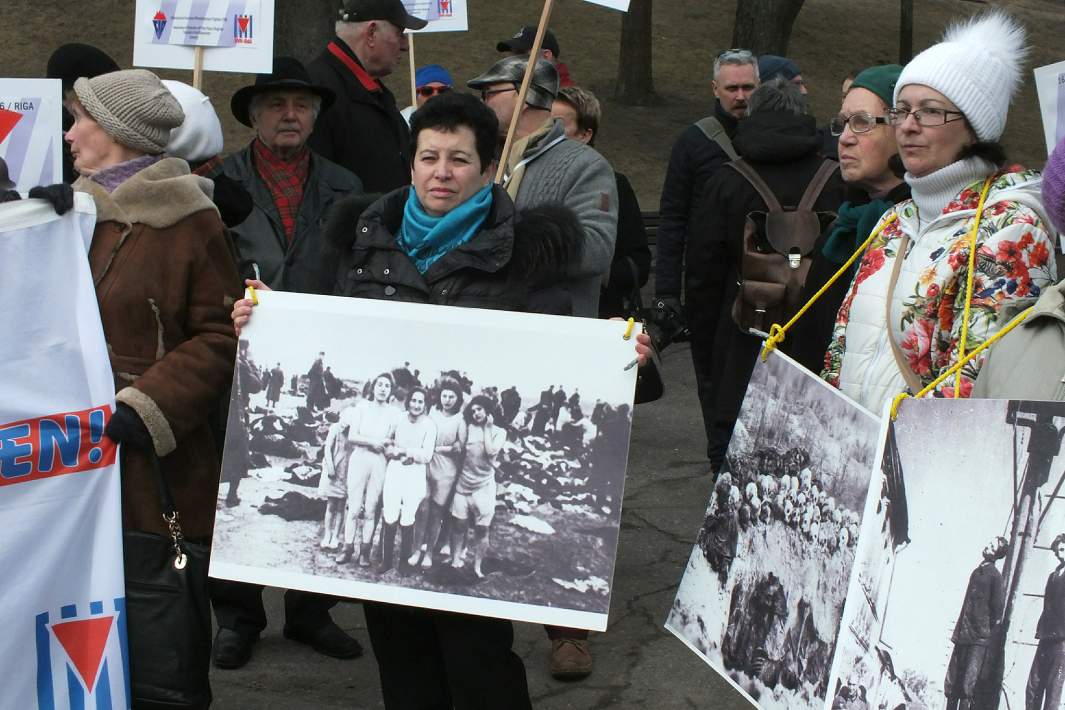 Представители антифашистских организаций держат плакаты на акции протеста во время марша бывших латышских легионеров СС и их сторонников в Риге