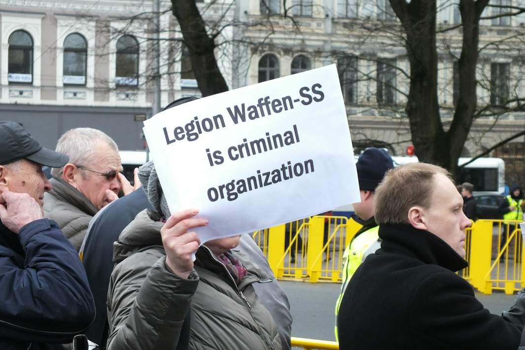 Представители антифашистских организаций держат плакаты с надписью «Они сражались за Адольфа Гитлера» на акции протеста во время марша бывших латышских легионеров СС и их сторонников в Риге